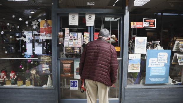 A pedestrian checks the hours on a closed magazine store in Montreal, Quebec, Canada, on Sunday, Jan. 9, 2022. Quebec Premier Francois Legault announced that the province's stores would be closed on three Sundays, with some exceptions, to curb coronavirus hospitalizations. Photographer: Christinne Muschi/Bloomberg