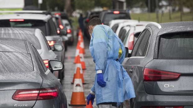 A healthcare worker adjusts traffic cones near cars queued at a drive-thru Covid-19 testing site in Sydney, Australia, on Wednesday, Dec. 29, 2021. Hospitalizations due to coronavirus in Australias most-populous state have reached the highest level since mid-October, as a surge in omicron cases throughout most of the nation pressures the health system.