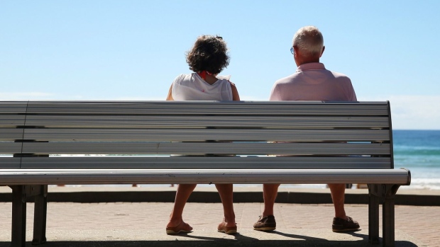 A woman and a man look out towards the beach while sitting on a bench in Sydney, Australia, on Wednesday, April 1, 2015. Photographer: Brendon Thorne