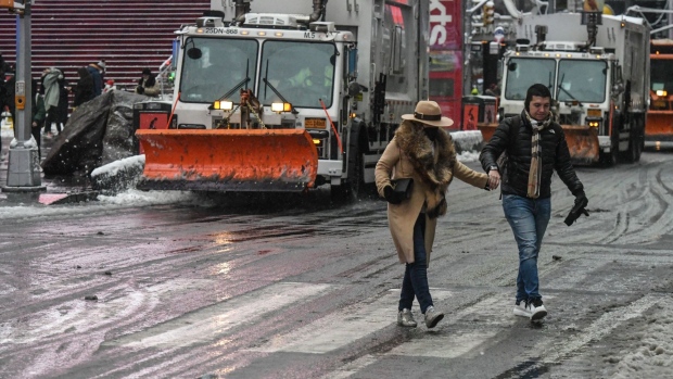 Pedestrians cross the street ahead of a snow plow New York, U.S., on Friday, Jan. 7, 2022. New York City experienced its first snow storm of the winter season with accumulations up to four inches in midtown Manhattan. Photographer: Stephanie Keith/Bloomberg