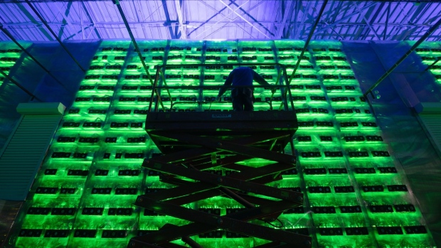 A technician on a cherry picker inspects racks of illuminated mining rigs at the Minto cryptocurrency mining center in Nadvoitsy, Russia, on Friday, Dec. 17, 2021. Bitcoin extended its five-week slide from an all-time high with risk sentiment across global financial markets dwindling. Photographer: Andrey Rudakov/Bloomberg