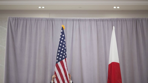 A woman adjusts an American flag before Shinzo Abe, Japan's prime minister, addresses members of the media following a meeting with U.S. President-elect Donald Trump in New York, U.S., on Thursday, Nov. 17, 2016. Abe said Trump was a trustworthy leader in comments after his first meeting with the President-elect, whose statements on trade and security have sparked concern in Japan. Photographer: John Taggart/Bloomberg