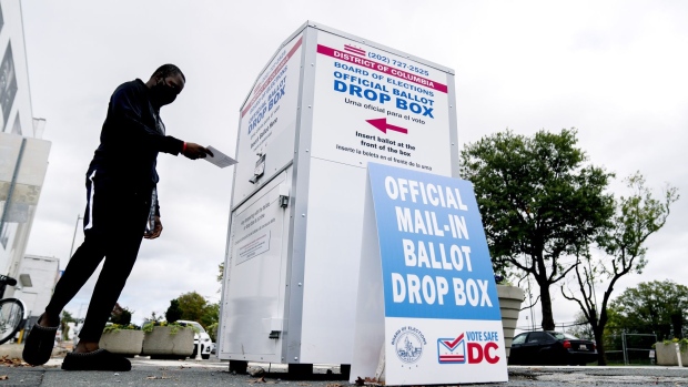 A voter wearing a protective mask deposits a ballot into an Official Ballot Drop Box in Washington, D.C., U.S., on Friday, Oct. 30, 2020. Early voting in the Presidential election reached 82 million ballots, almost 60% of the total turnout in 2016, according to the U.S. Elections Project. Photographer: Stefani Reynolds/Bloomberg