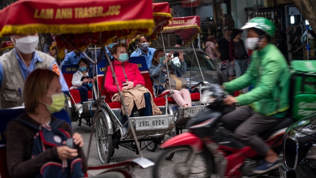 HANOI, VIETNAM - MARCH 15: Foreign tourists wear face masks amid concerns of the spread of the COVID-19 Coronavirus while taking a city tour on cyclo on March 15, 2020 in Hanoi, Vietnam. As from March 16, 2020, Vietnam requires that foreign citizens in Vietnam as well as Vietnamese citizens must wear face masks in public places where there are many people, such as supermarkets, airports, bus terminal or public transport means. The authorities of Hanoi & Ho Chi Minh City also asked all forms of entertainment establishments including bars, karaoke bars and several tourist sites to close until the end of March. Vietnam has so far confirmed 53 cases of coronavirus infections, with 16 having fully recovered. (Photo by Linh Pham/Getty Images)