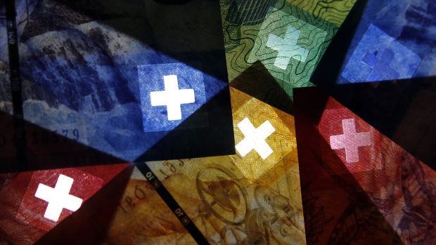 The cross of the Swiss national flag sits on Swiss franc banknotes in an arranged photograph in Bern, Switzerland, on Saturday, March 14, 2020. Pressure is intensifying on the Swiss National Bank to join policy makers around the world who’ve cut interest rates and increased stimulus in response to the coronavirus outbreak. Photographer: Stefan Wermuth/Bloomberg