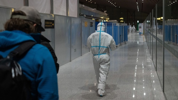 BEIJING, CHINA - JANUARY 24: An official decked in personal protective equipment leads passengers to arrivals registration and PCR testing stations as they disembark from a plane on January 24, 2022 in Beijing, China. With just over a week to go until the opening ceremony, final preparations are being made in Beijing ahead of the forthcoming 2022 Winter Olympics. (Photo by Carl Court/Getty Images)