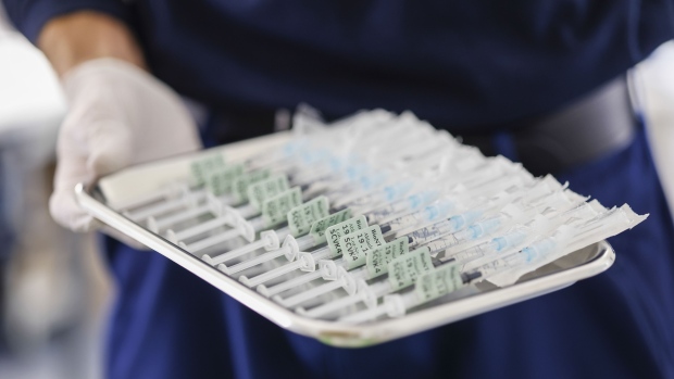 A healthcare worker holds a tray of syringes filled with the Pfizer-BioNTech vaccine for Covid-19 at a vaccination center in Munich, Germany, on Thursday, Dec. 2, 2021. Germany is poised to clamp down on people who aren’t vaccinated against Covid-19 and drastically curtail social contacts to ease pressure on increasingly stretched hospitals.