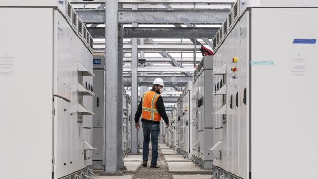 A worker walks between power inverters outside the battery building at the Vistra Corp. Moss Landing Energy Storage Facility in Moss Landing, California, U.S., on Tuesday, April 20, 2021. The facility is the world's largest battery energy storage system.
