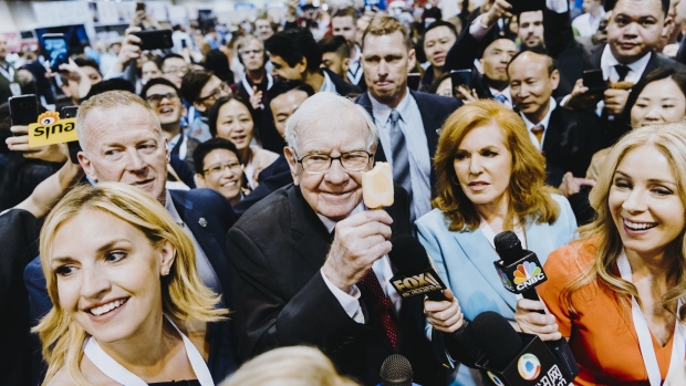 Warren Buffett, chairman and chief executive officer of Berkshire Hathaway Inc., center left, eats a Dairy Queen vanilla orange ice cream bar while touring the shopping floor ahead of the company's annual meeting in Omaha, Nebraska, U.S., on Saturday, May 4, 2019. Buffett's Berkshire Hathaway agreed earlier this week to make the investment in Occidental to help the oil producer with its $38 billion bid for Anadarko Petroleum Corp.