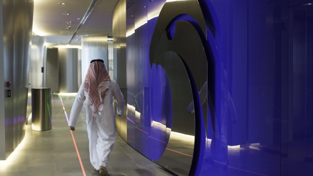 An employee passes the logo of the Abu Dhabi National Oil Company (ADNOC) displayed on a wall at the company's headquarters in Abu Dhabi, United Arab Emirates, on Thursday, Feb. 22, 2018. Adnoc is seeking to create world’s largest integrated refinery and petrochemical complex at Ruwais.