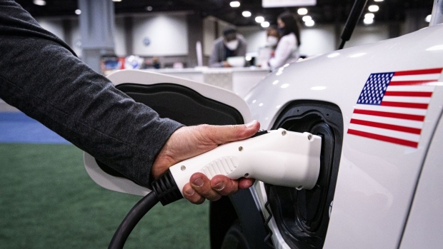 An exhibitor demonstrates plugging in a charging port for a Ford Motor Co. Mustang during the Washington Auto Show on Jan. 21, 2022.