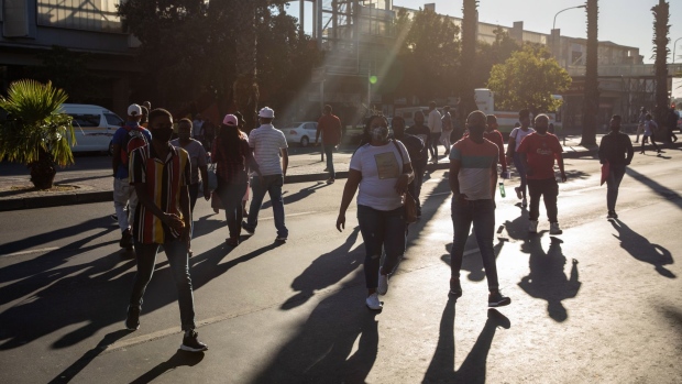 Commuters wearing protective face masks cross Strand Street in Cape Town, South Africa, on Monday, Jan. 11, 2021. The pandemic and restrictions imposed to contain it have devastated Africa's most industrialized economy, and the extension of curbs that came into effect at the height of the holiday season bode ill for efforts to engineer a rebound.
