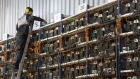 An engineer on a ladder inspects racks of application-specific integrated circuit (ASIC) mining devices and power units at the BitCluster cryptocurrency mining farm in Norilsk, Russia, on Sunday, Dec. 20, 2020. Norilsk may soon be famous for a different type of mining — it now hosts the Arctic's first crypto farm for producing new Bitcoins.