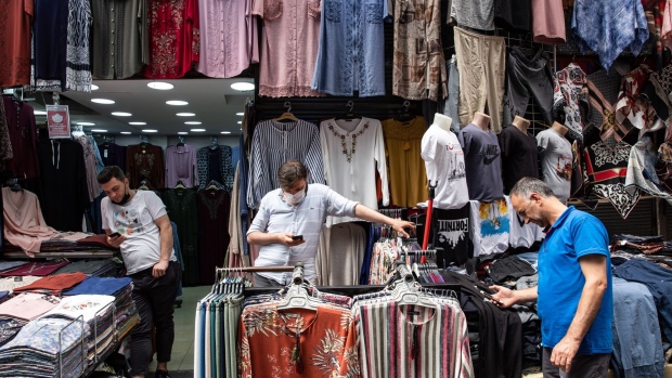 Store owners check their mobile phones outside a clothes store in the Eminonu district of Istanbul, Turkey, on Tuesday, Aug. 11, 2020. A day after the latest call from President Recep Tayyip Erdogan for lower borrowing costs to boost economic growth, the central bank reduced the cheaper liquidity it provides to primary dealers as part of its open market operations to zero from Aug. 12, according to a statement on Tuesday. Photographer: Kerem Uzel/Bloomberg