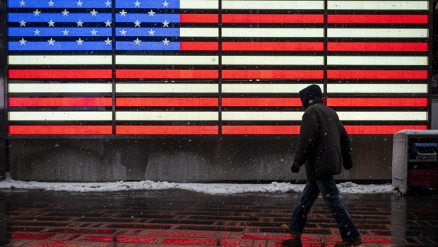 A pedestrian walks through Times Square during a winter storm in New York, U.S., on Friday, Feb. 19, 2021. A meandering storm will leave New York and the Northeast with up to 8 inches (20 centimeters) of snow through Friday, while ice and cold continue to plague Texas.
