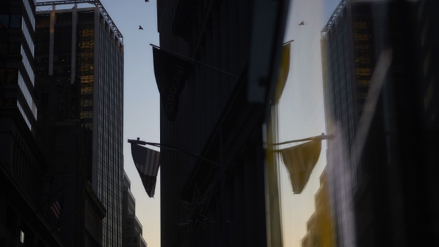 An American flag is reflected in the window of a building near the New York Stock Exchange (NYSE) in New York, U.S., on Thursday, Dec. 27, 2018. Volatility returned to U.S. markets, with stocks tumbling back toward a bear market after the biggest rally in nearly a decade evaporates. Photographer: John Taggart/Bloomberg