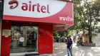 A pedestrian using a mobile phone walks past a Bharti Airtel Ltd. store in Mumbai, India, on Sunday, Jan. 19, 2020. Telecom companies including Bharti and Vodafone Idea Ltd. have sought more time from India's top court to pay $13 billion in past dues as they plan to negotiate with the government, people with knowledge of the matter said.