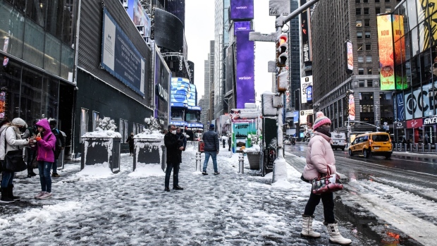 Pedestrians walk through Times Square during a snow storm in New York, U.S., on Friday, Jan. 7, 2022. New York City experienced its first snow storm of the winter season with accumulations up to four inches in midtown Manhattan.