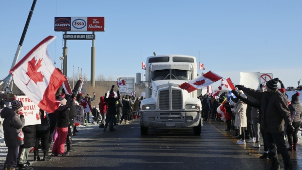 A man poses for a photo with one of many trucks parked along Wellington St. ahead of a demonstration in Ottawa, Ontario, Canada, on Friday, Jan. 28, 2022. A convoy of aggrieved truckers who have become a global cause celebre for opponents of vaccine mandates rolled into Canada's capital this weekend, putting the nation on tenterhooks amid heightened worries the protest could lead to clashes with police.