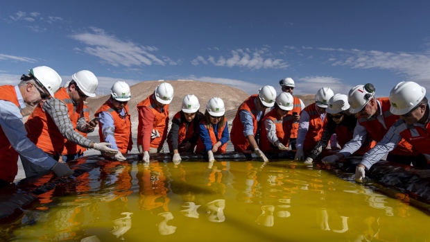 Visitors inspect a brine pool at a Sociedad Química y Minera de Chile (SQM) lithium mine on the Atacama salt flat in the Atacama Desert, Chile, on Wednesday, May 29, 2019. Almost three-quarters of the world’s lithium raw materials come from mines in Australia or briny lakes in Chile, giving them leverage with customers scrambling to tie-up supplies. The mining nations hope to bring refining and manufacturing plants that could help kickstart domestic technology industries.
