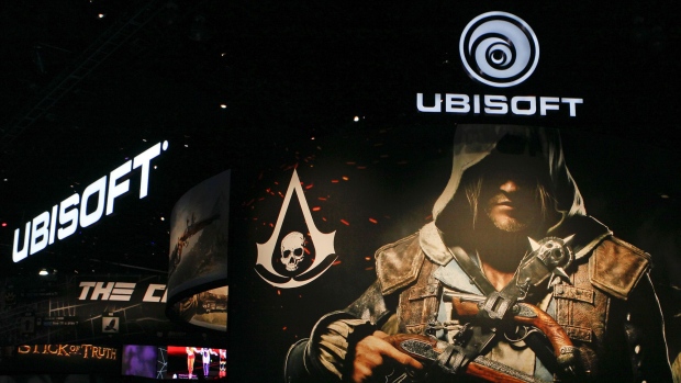 Attendees walk past signage for UbiSoft Entertainment SA's Assassin's Creed IV: Black Flag video game during the E3 Electronic Entertainment Expo in Los Angeles in 2013. 