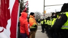 Police officers move in to clear traffic and protesters blocking access to the Ambassador Bridge during a demonstration in Windsor, Ontario, Canada, on Saturday, Feb. 12, 2022. Police in Ontario have begun to clear out people who've been blocking the Ambassador Bridge that connects Canada with Detroit in a protest against Covid-19 restrictions.