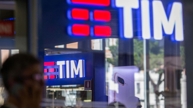 A pedestrian uses a mobile device as she walks past a Telecom Italia SpA (TIM) store, in Rome, on Sept. 25, 2017.