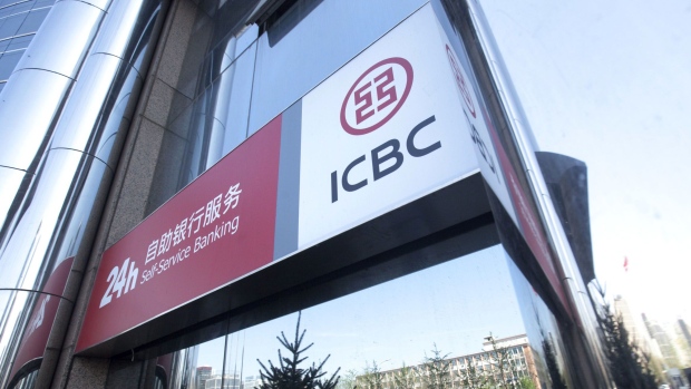 A woman is seen reflected in a window as she speaks on her mobile phone, outside a branch of the Industrial & Commercial Bank of China Ltd. (ICBC) in Beijing.