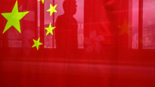 A pedestrian is seen through a Chinese flag ahead of the anniversary of Hong Kong's return to Chinese in Hong Kong, China, on Wednesday, June 30, 2021. The national security law China imposed on Hong Kong a year ago today was much more than a piece of legislation: It showed Beijing was now running the show in the former British colony. Photographer: Lam Yik/Bloomberg
