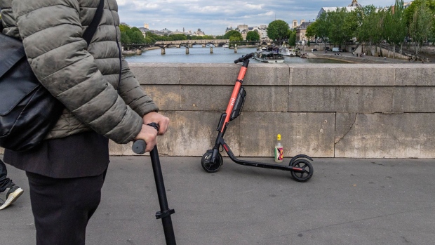 A Voi Technology AB public hire e-scooter rests on a bridge over the River Seine in Paris.