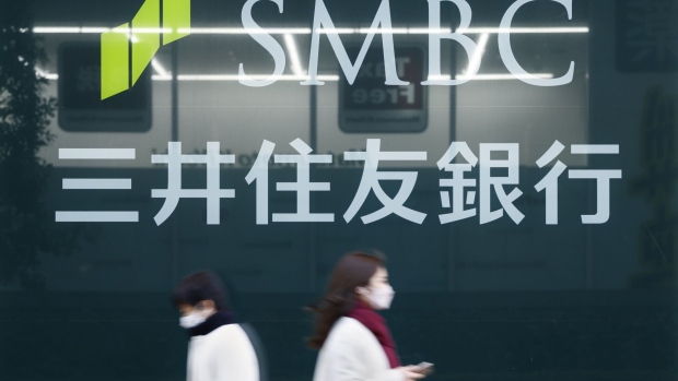 Pedestrians in front of signage for Sumitomo Mitsui Banking Corp., a unit of Sumitomo Mitsui Financial Group Inc. (SMFG), outside a branch in Tokyo, Japan, on Monday, Jan. 31, 2022. Sumitomo Mitsui Financial Group is scheduled to release its third-quarter earnings announcement on February 2. Photographer: Kiyoshi Ota/Bloomberg