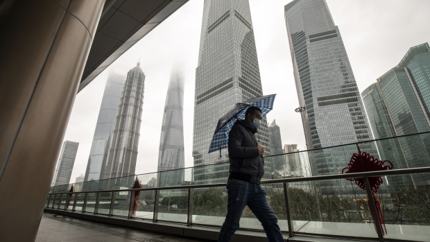 A pedestrian passes buildings in Pudong's Lujiazui Financial District in Shanghai, China, on Monday, Feb. 7, 2022. Asian stocks were mixed amid a rally in China on Monday as the nation’s markets reopened from a holiday, while the prospect of global monetary tightening continued to weigh on bonds. Photographer: Qilai Shen/Bloomberg