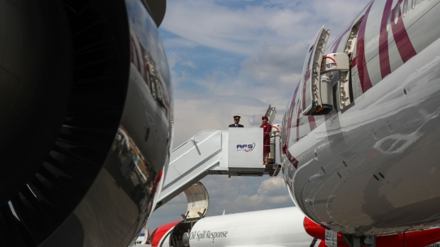 Aircrew stand at the top of steps at the entrance to a Airbus SE A350 passenger aircraft, operated by Qatar Airways, on the opening day of the Farnborough International Airshow (FIA) 2018 in Farnborough, U.K., on Monday, July 16, 2018. The air show, a biannual showcase for the aviation industry, runs until July 22.