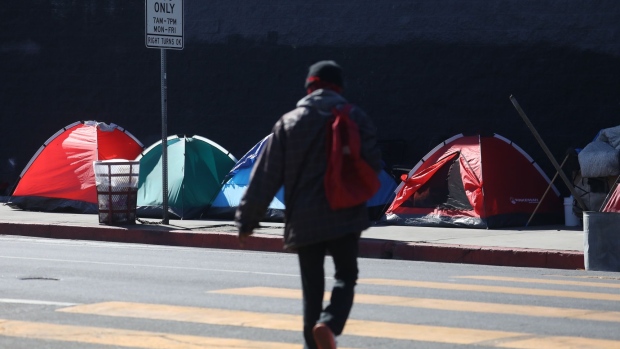 A person experiencing homelessness walks to their tent in the Skid Row neighborhood of Los Angeles, California, U.S., on Thursday, Feb. 24, 2022. Thousands of volunteers will comb the streets of Los Angeles for the next three days to conduct the first annual count of the region’s homeless population since the pandemic began.