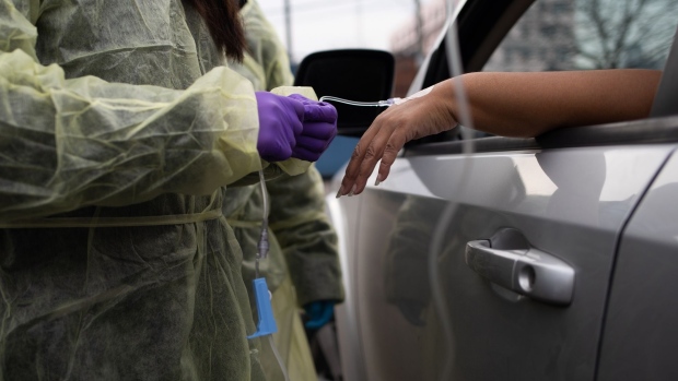 A health-care worker attaches an IV infusion to a patient's hand during a monoclonal antibody treatment in the parking lot at a health center in Detroit, Michigan.