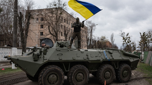 A soldier waves the Ukrainian national flag while standing on top of an armoured personnel carrier in Hostomel, Ukraine, on April 8, 2022.