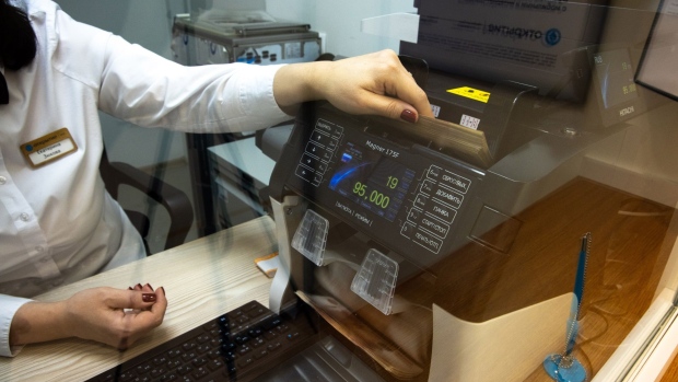 An employee places 5000 ruble banknotes into a counting machine inside an Otkritie Bank FC PJSC branch in Moscow, Russia, on Tuesday, Jan. 18, 2022. UniCredit SpA is interested in a potential takeover of rescued Russian lender Otkritie Bank, as Chief Executive Officer Andrea Orcel explores M&A opportunities to improve the group’s profitability. Photographer: Andrey Rudakov/Bloomberg