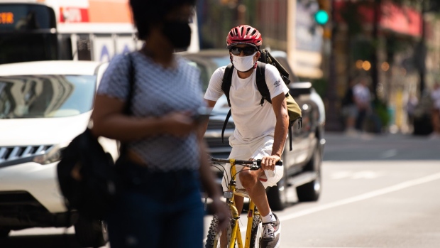 A cyclist wears a protective mask while riding in downtown Philadelphia, Pennsylvania, U.S., on Thursday, Aug. 12, 2021. The City of Philadelphia issued new mask mandates to protect against the Delta variant, requiring masks to be worn indoors and at large outdoor gatherings.
