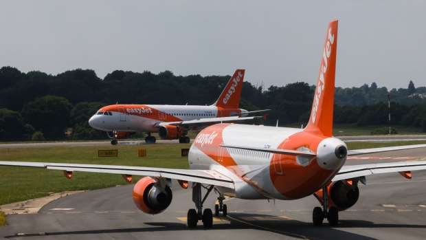An Easyjet Plc aircraft, left, lands at London Luton Airport in Luton, U.K., on Monday, July 19, 2021. While fully vaccinated tourists headed for the Mediterranean were cheered by the removal of quarantine requirements on their return, people bound for France hit out a decision late Friday that means they’ll still need to self-isolate.