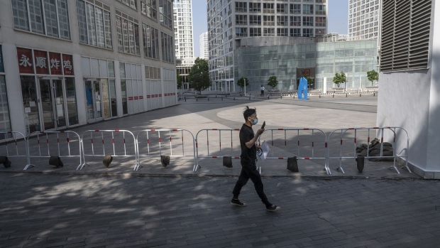 BEIJING, CHINA - MAY 05: A delivery driver walks by an empty office complex as he looks to deliver a package in the Central Business District, after the government recommended people work from home to prevent the spread of COVID-19, on May 5, 2022 during morning rush hour in Beijing, China. China is trying to contain a spike in coronavirus cases in the capital Beijing after dozens of people tested positive for the virus in recent days, causing local authorities to initiate mass testing in most districts, close schools, and ban gatherings and inside dining in all restaurants, and to lockdown some neighbourhoods in an effort to maintain the country's zero COVID strategy. (Photo by Kevin Frayer/Getty Images) Photographer: Kevin Frayer/Getty Images AsiaPac