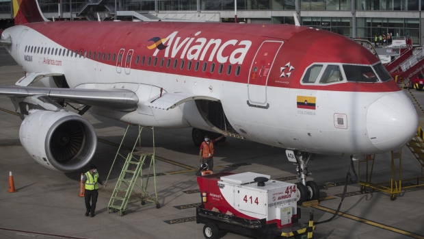 Workers stand beside an Avianca Holdings SA aircraft before flights resume at El Dorado International Airport (BOG) in Bogota, Colombia, on Monday, Aug. 31, 2020. Mayor Claudia Lopez announced that domestic flight operations will resume on September 1, although international Flights are still banned except for humanitarian or cargo shipments.