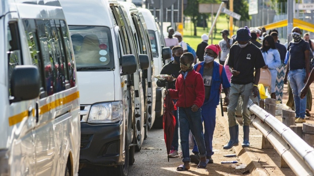 Commuters wear protective face masks as they queue for taxi vans in Pretoria, South Africa, on Monday, Feb. 8, 2021. South Africa will temporarily halt the rollout of AstraZeneca Plc’s vaccine and accelerate its supply of shots from Johnson & Johnson and Pfizer Inc. after a trial showed the shot had limited efficacy against a new variant of the virus first identified in the country late last year. Photographer: Waldo Swiegers/Bloomberg