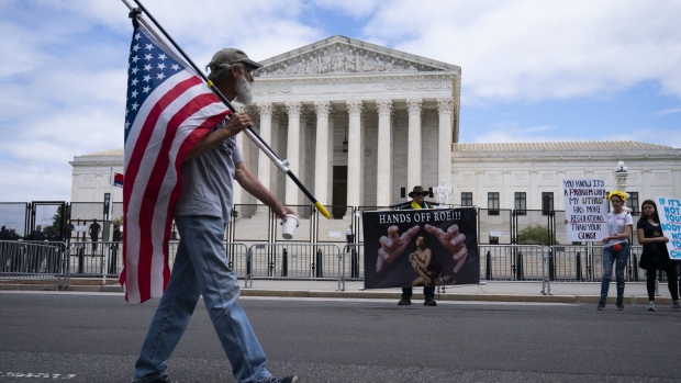 A pedestrians carries an American flag near abortion rights demonstrators outside the US Supreme Court in Washington, D.C., US, on Wednesday, May 11, 2022. Senate Democrats were blocked in their attempt to enshrine abortion rights in federal law in a vote that highlighted both the deep divide on the politically explosive issue and the party's schism over ending the filibuster to achieve their goals.