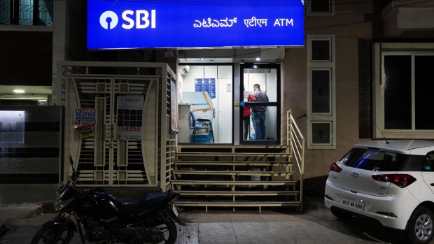 Customers use an automated teller machine (ATM) at a State Bank of India Ltd. (SBI) branch at night in Bengaluru, India, on Tuesday, May 7, 2019. State Bank of India, the country's largest lender by assets, posted a fourth-quarter profit that missed all analyst forecasts as provisions for bad loans rose from the previous three-month period.
