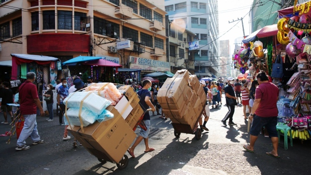 Workers carry boxes on trolleys past stalls at Divisoria Market in Manila, the Philippines, on Sunday, Dec. 5, 2021. The Philippines had loosened virus restrictions in recent weeks as Covid-19 infections declined but with the emergence of the virus variant however, Metro Manila will remain under Alert Level 2 to December 15 and the Southeast Asian nation has rolled back its reopening totourists.