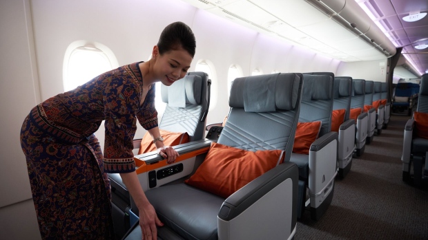 A flight attendant arranges a premium class seat of a Singapore Airlines Ltd. Airbus SE A380 aircraft with refitted cabins during a media tour at Changi Airport in Singapore, on Thursday, Dec. 14, 2017. In the battle to fill their seats with high fliers, the worlds top airlines are rolling out evermore luxurious options for top-tier travelers.