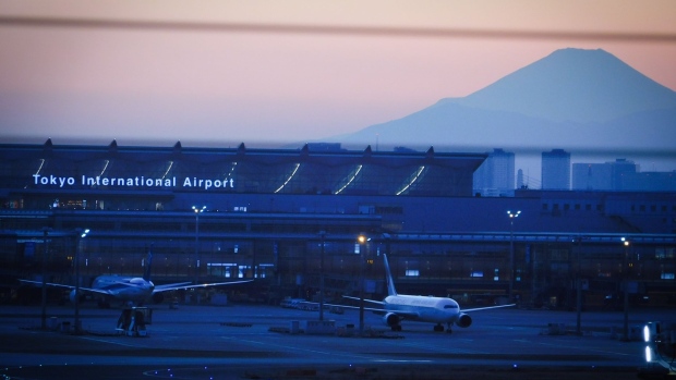 A view of Mount Fuji at dusk from Haneda Airport in Tokyo, Japan, on Saturday, Feb. 26, 2022. The first phase of Japan's easing on quarantine rules starts from March 1, when new foreign entrants except for tourists will be admitted. The government will cap the number of daily arrivals at 5,000 compared with the current 3,500 for the time being.