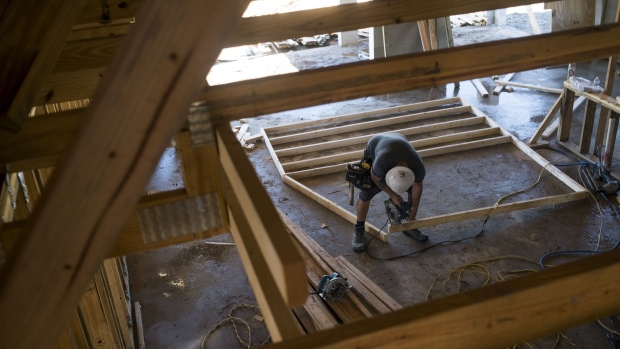 A worker saws a section of lumber inside a home under construction at the M/I Homes Inc. Bougainvillea Place housing development in Ellenton, Florida, U.S., on Thursday, July 6, 2017.