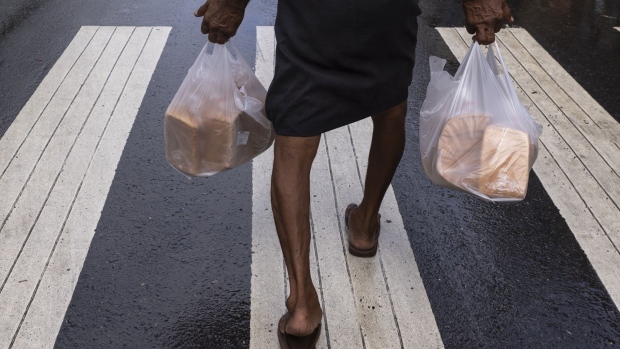 A man carries two bags of bread in Colombo, Sri Lanka, on Monday, May 16, 2022. Sri Lanka has been rattled by power cuts, food shortages, and a currency in free fall, which fueled protests and pushed Prime Minister Mahinda Rajapaksa to resign.