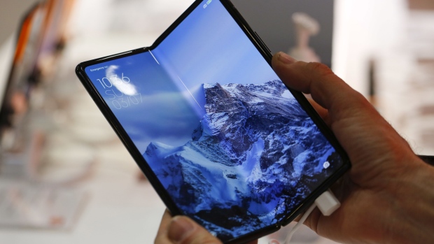 An attendee handles the Xiaomi Mi Mix Fold foldable smartphone at the Xiaomi Corp. stand on the opening day of the MWC Barcelona at the Fira de Barcelona venue in Barcelona, Spain, on Monday, Feb. 28, 2022. Over 1,800 exhibitors and attendees from 183 countries will attend the annual event, which runs from Feb. 28 to March 3.
